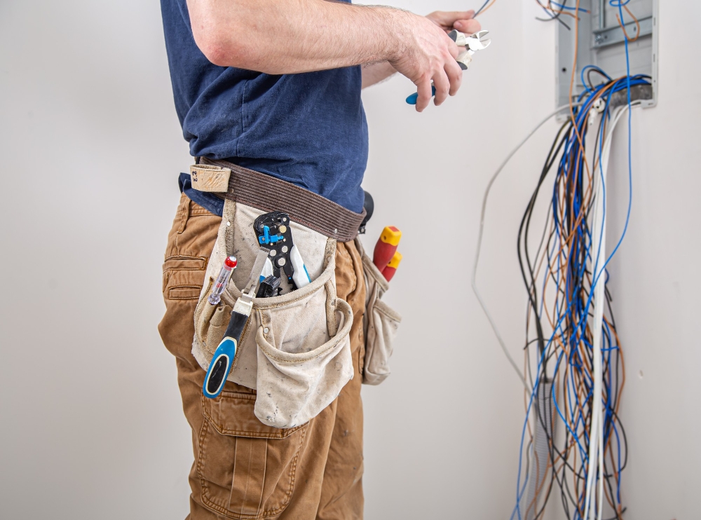 electrician-builder-work-examines-cable-connection-electrical-line-fuselage-industrial-switchboard-professional-overalls-with-electrician-s-tool